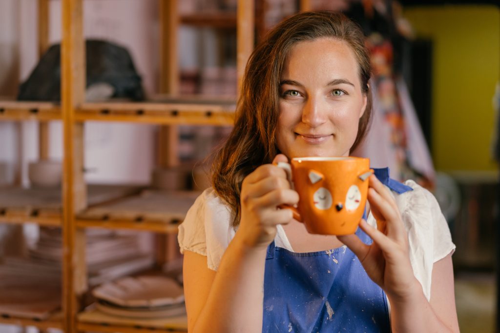 Girl in White Shirt Holding Blue Ceramic Mug